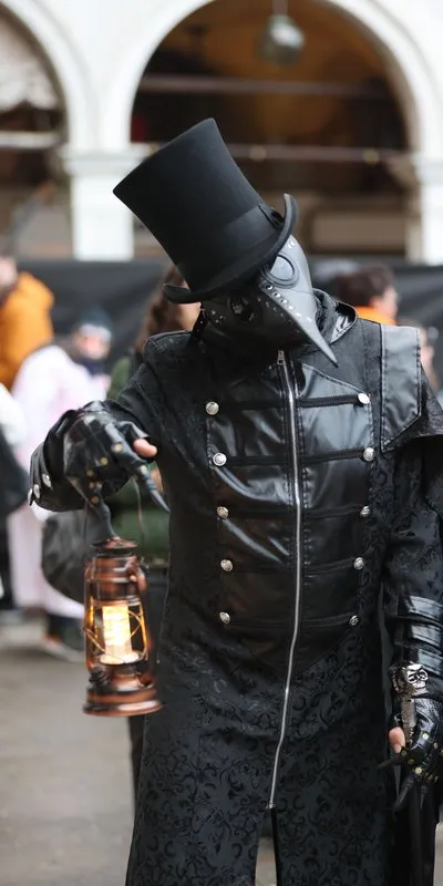 Persona disfrazada de médico de la peste con abrigo negro, sombrero de copa, máscara con pico de pájaro y un farol en la mano